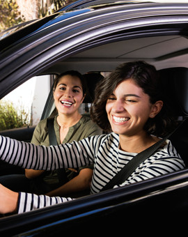Two woman driving in car smiling